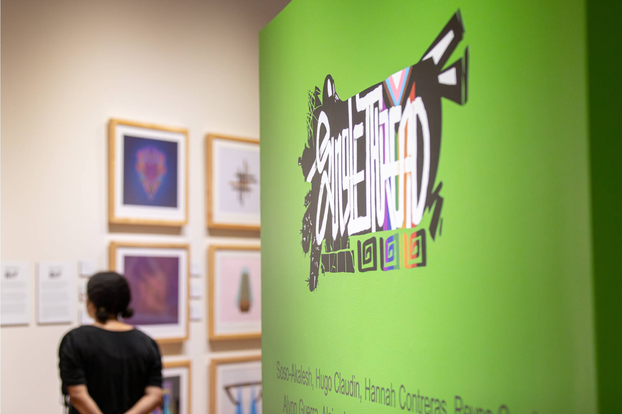 A photograph of a visitor in the PAC Gallery next to artwork and a green title wall